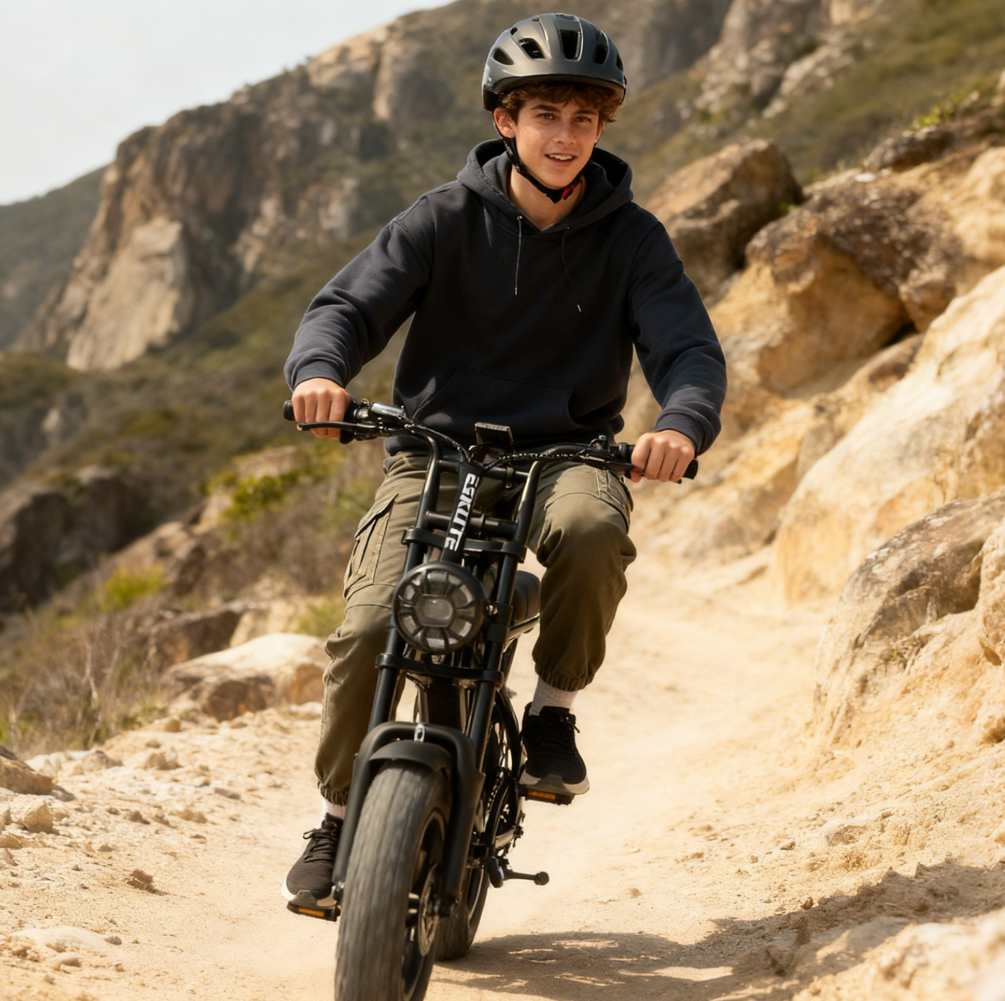 Person riding a bike on a rocky trail with mountains in the background